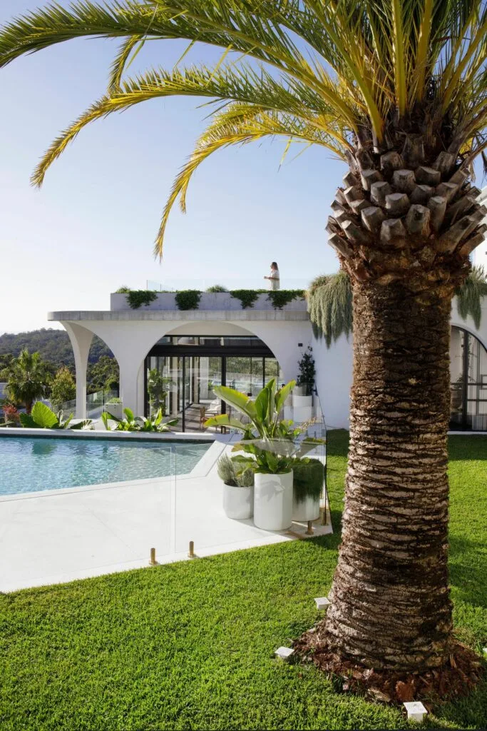 contemporary swimming pool with white home exterior and arched architectural details