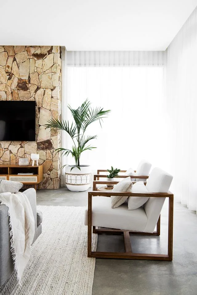 light and bright living room with sheer white curtains and stone fireplace