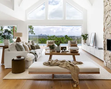 Light coastal living room with stone fireplace and A-frame windows