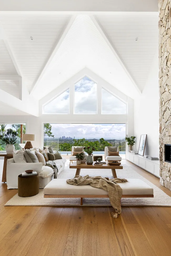 Light coastal living room with stone fireplace and A-frame windows