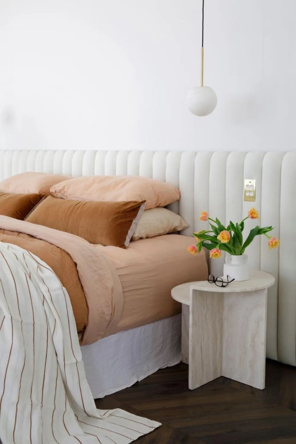 White bedroom with bed linen in shades of terracotta and peach