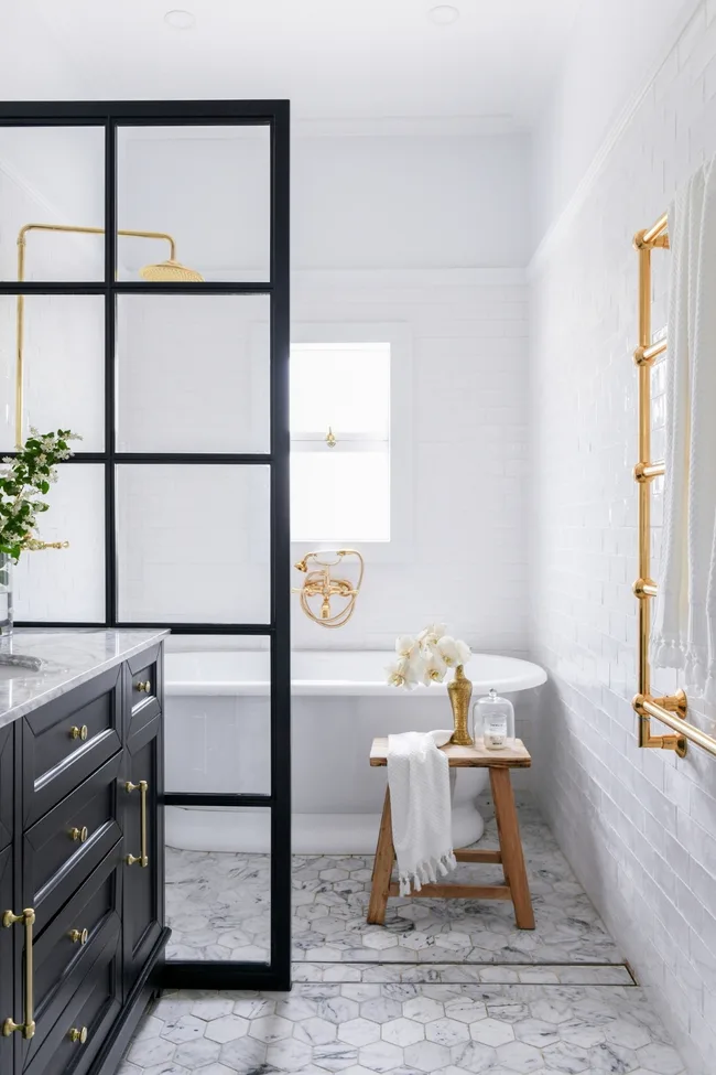 White bathroom with black shower frame and brass tapware