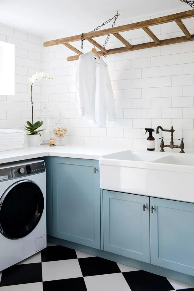 Laundry with pale blue cabinetry and subway tiles