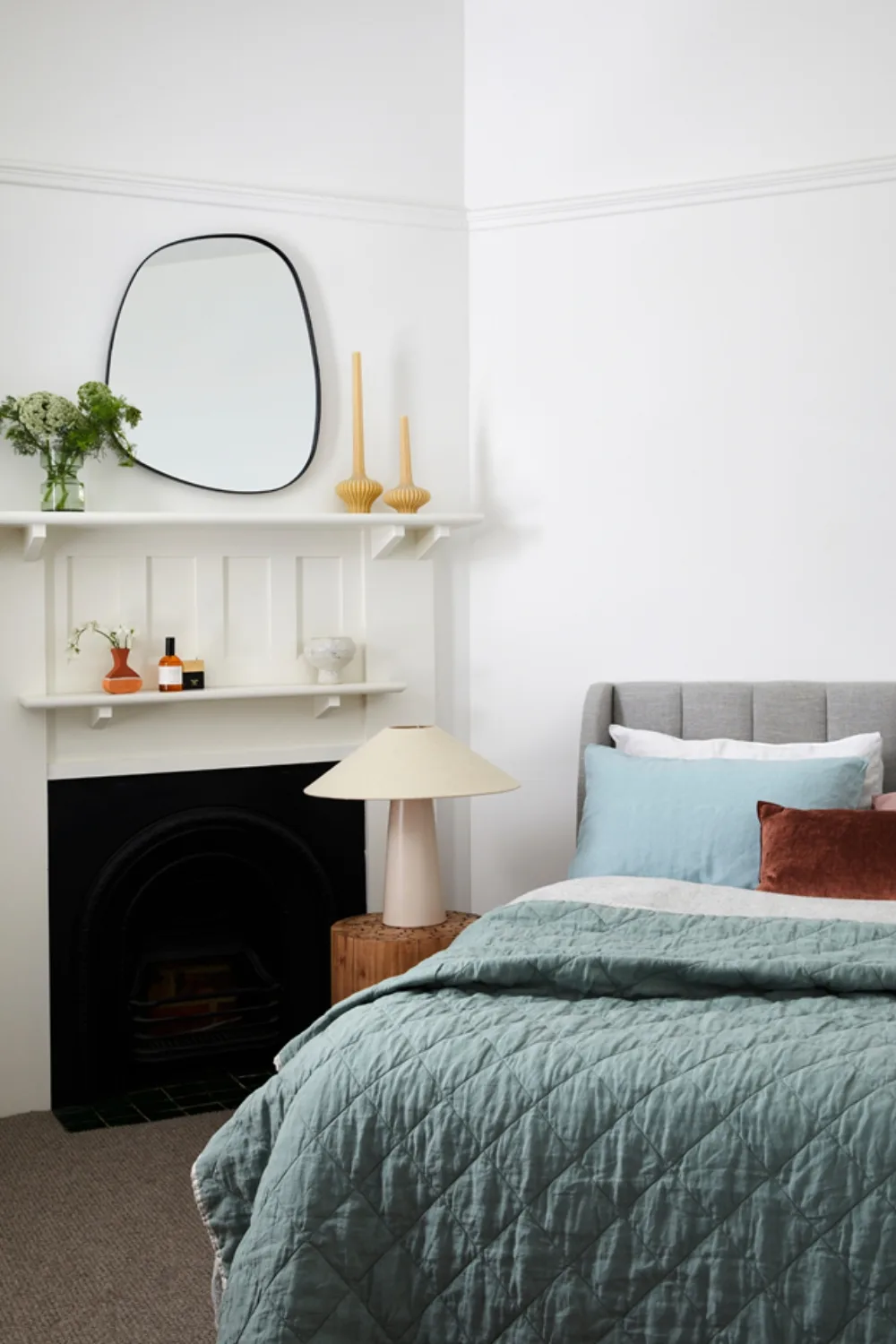 Neutral bedroom with sage green bedspread and original fireplace