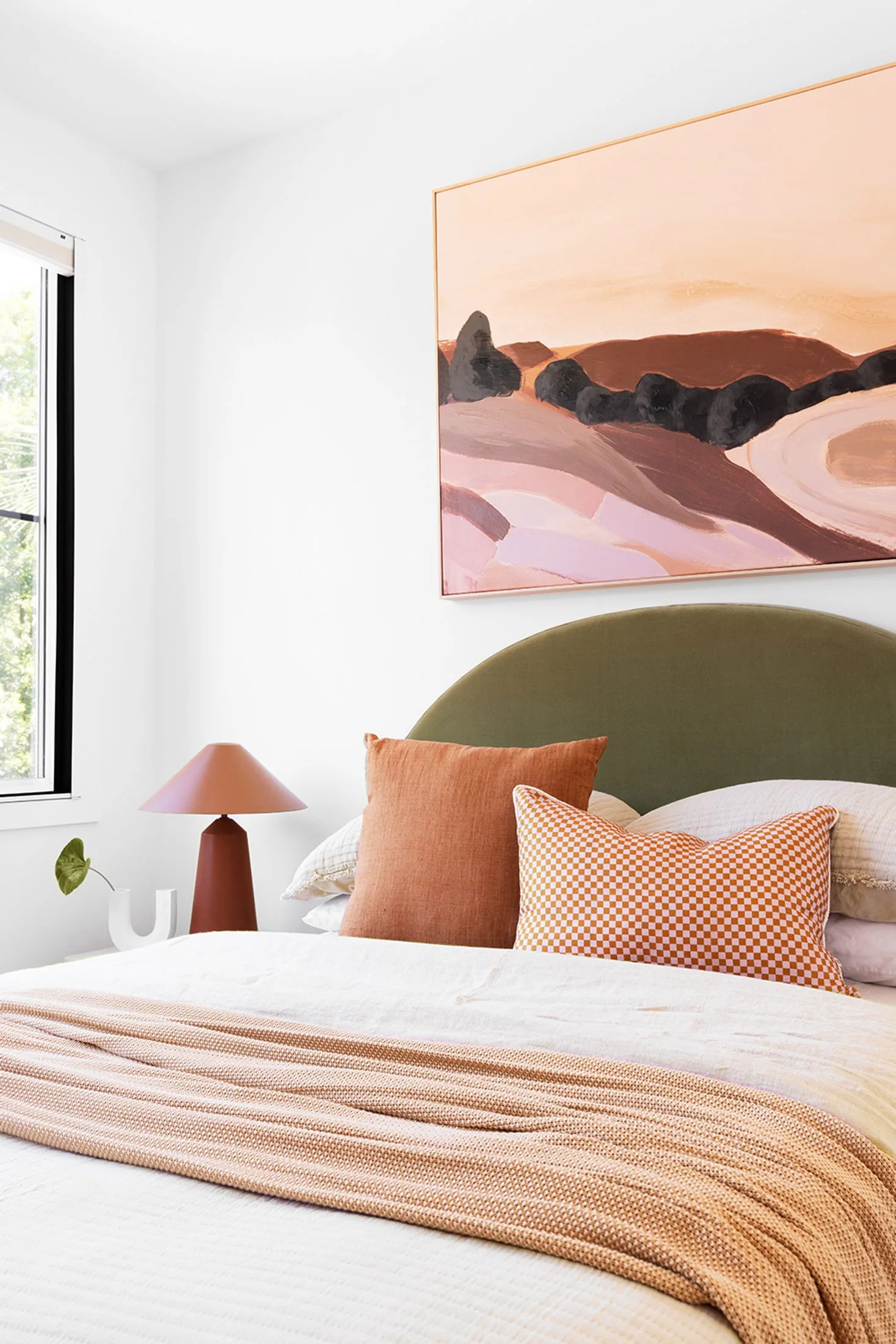 Guest bedroom with olive and terracotta artwork and bedlinen