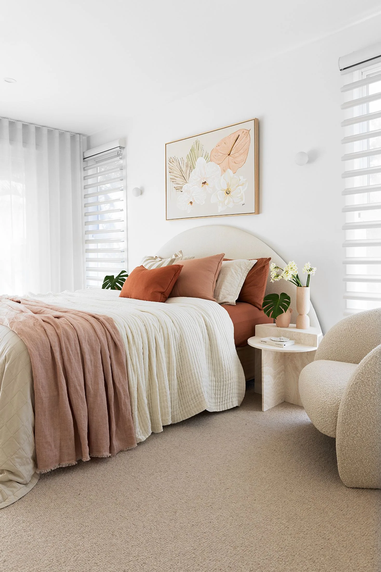 main bedroom with upholstered arched bedhead and bucle armchair