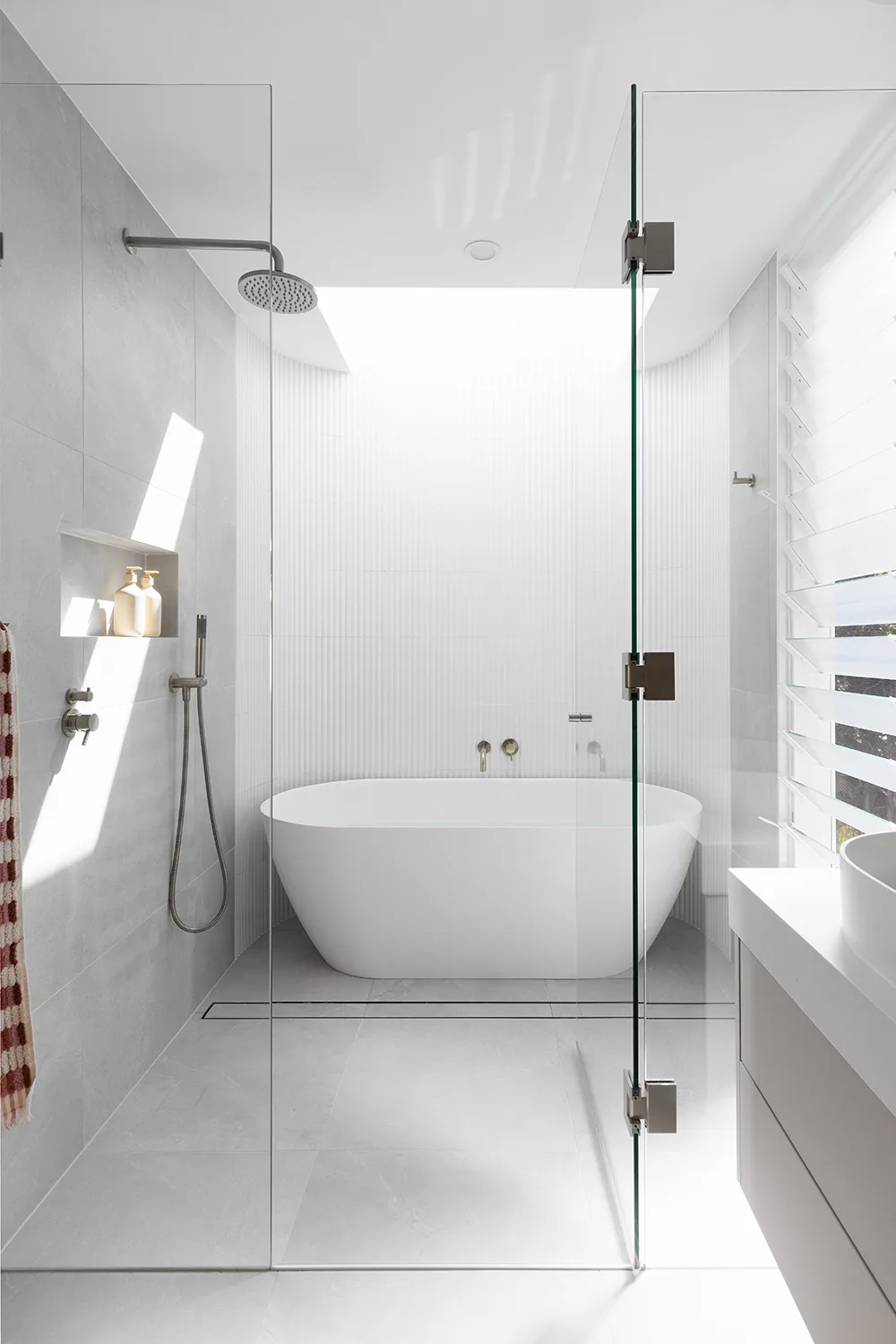 Minimalist bathroom with freestanding bathtub and white finger tiles