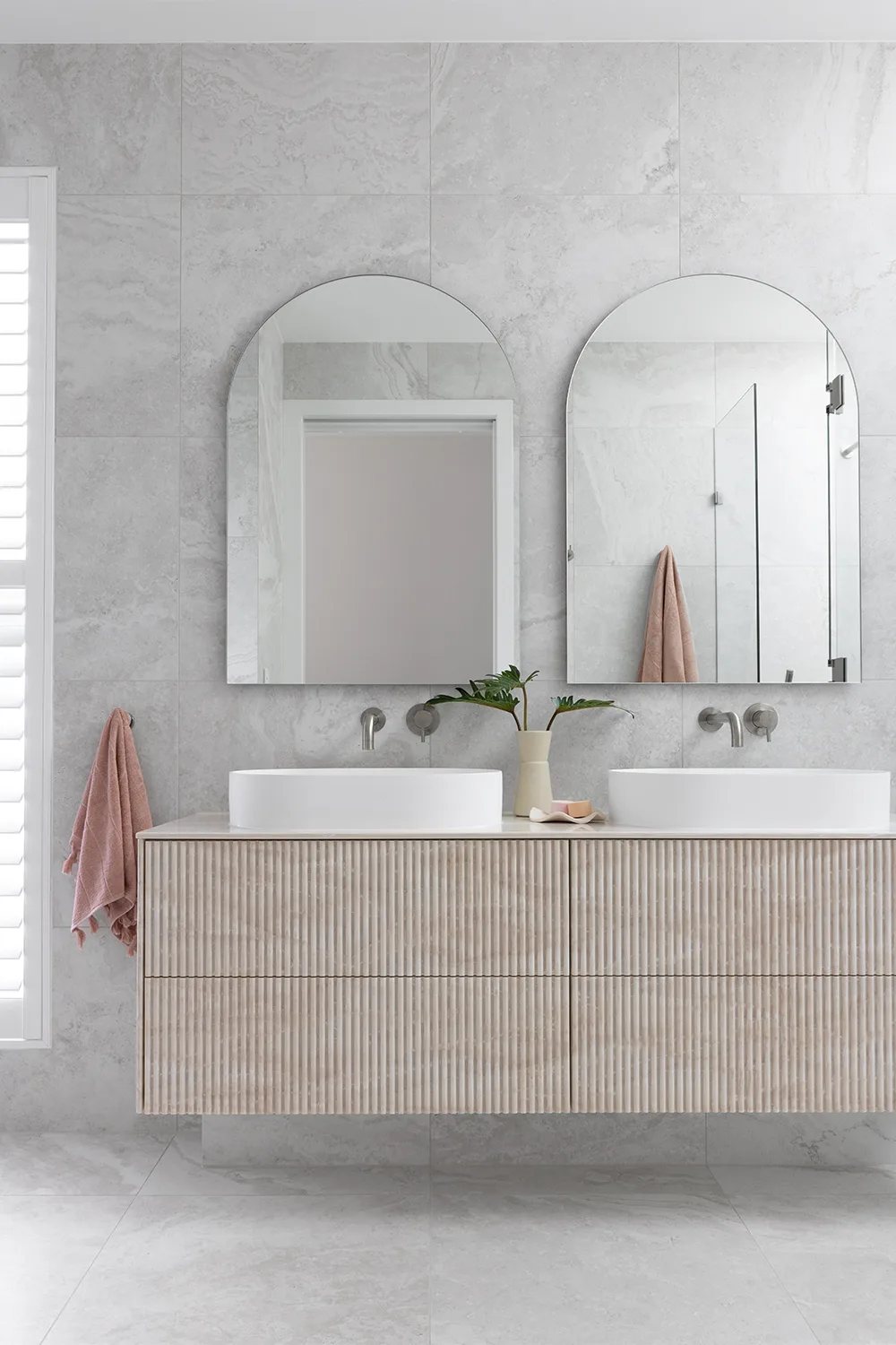 Minimalist ensuite with grey wall tiles and arched mirrors