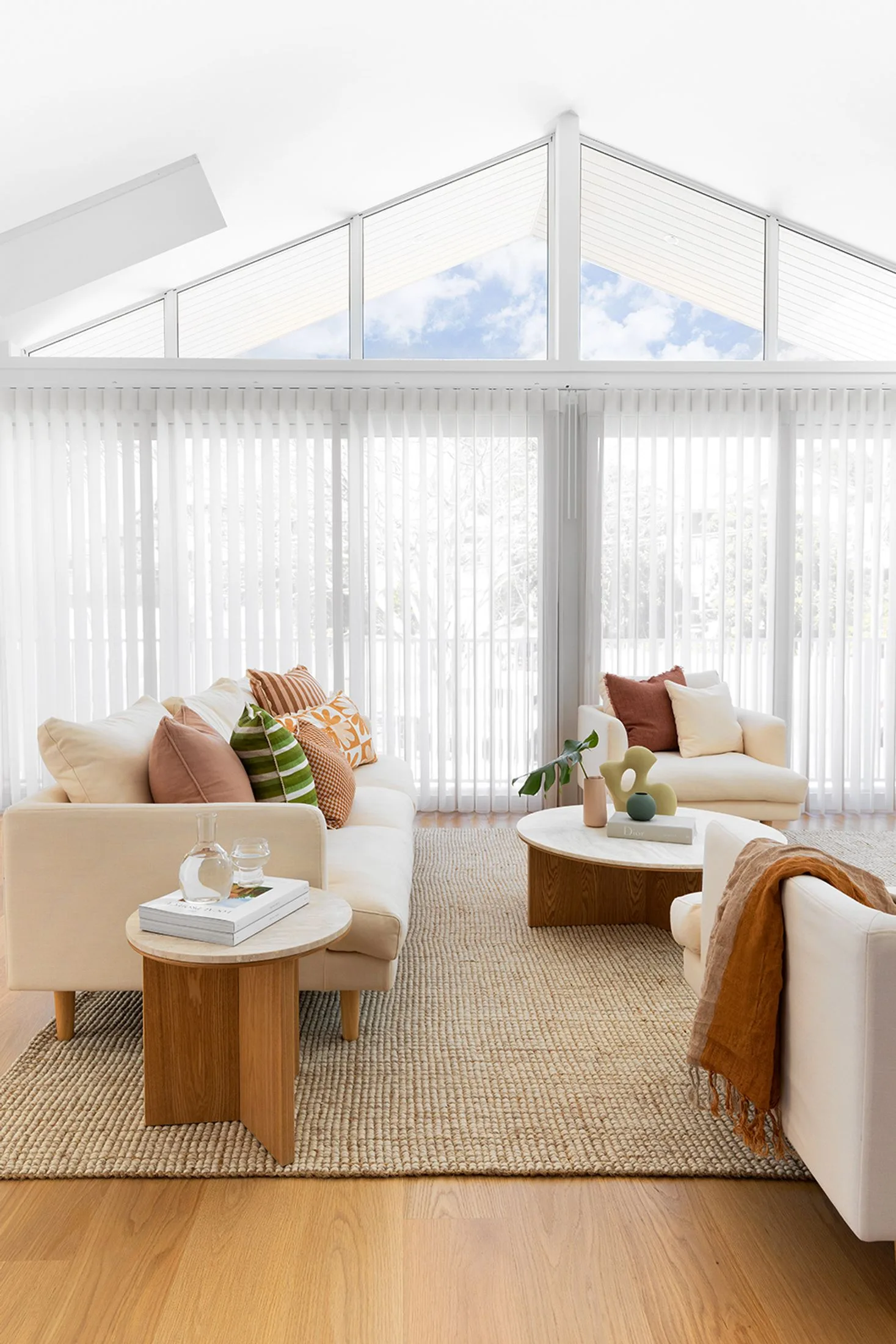 Contemporary family living room in all white with pitched ceilings and a natural jute rug