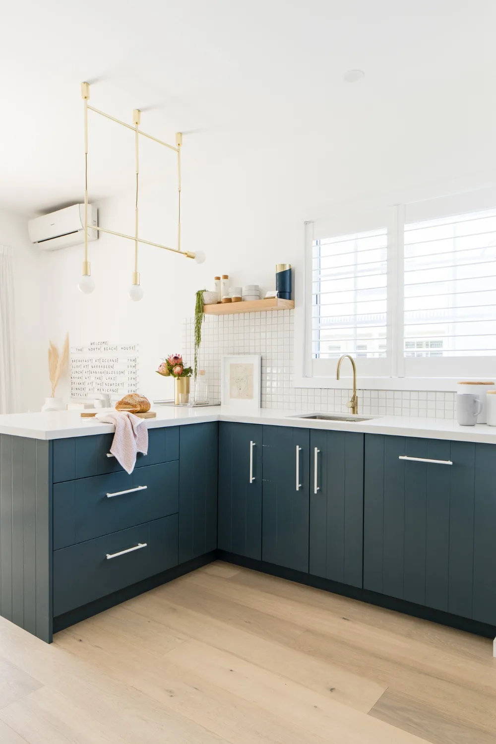 Dark green kitchen with white tiled splashback and gold hardware