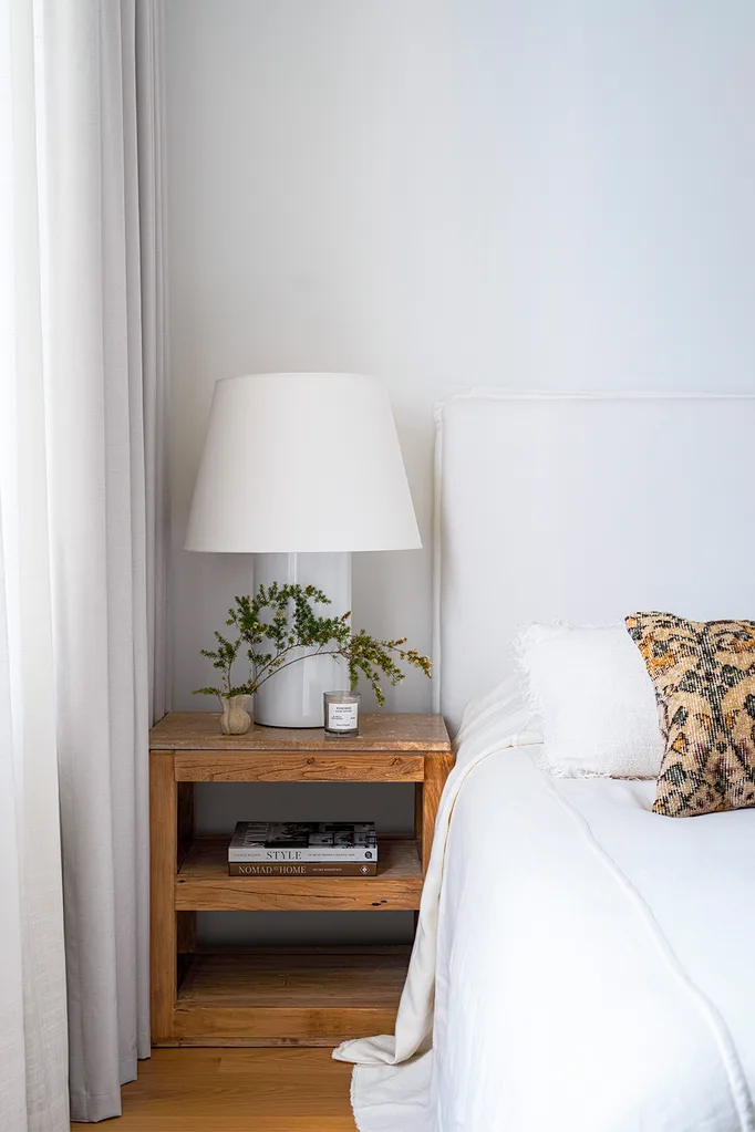 Contemporary coastal bedroom with boucle upholstered bedhead and white lamp