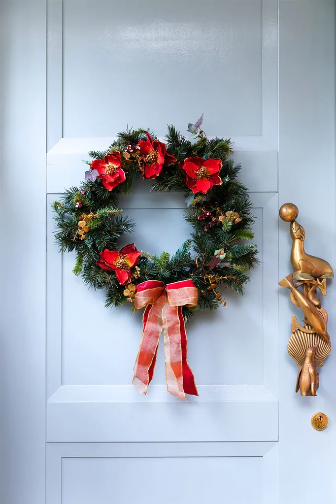 Pale blue front door with faux pine Christmas wreath and red ribbons