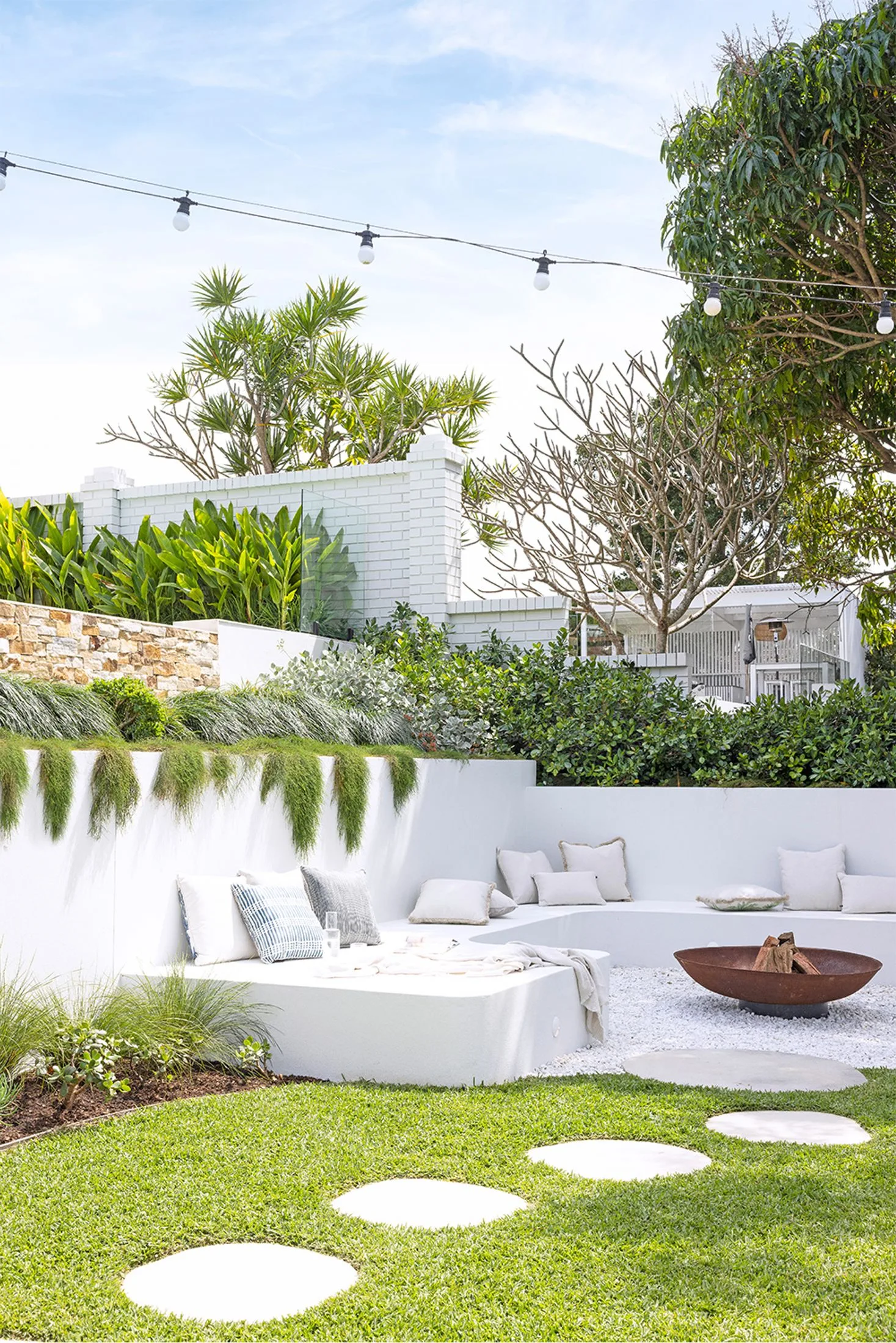 White landscaped garden with rendered built-in bench seat around a fire pit