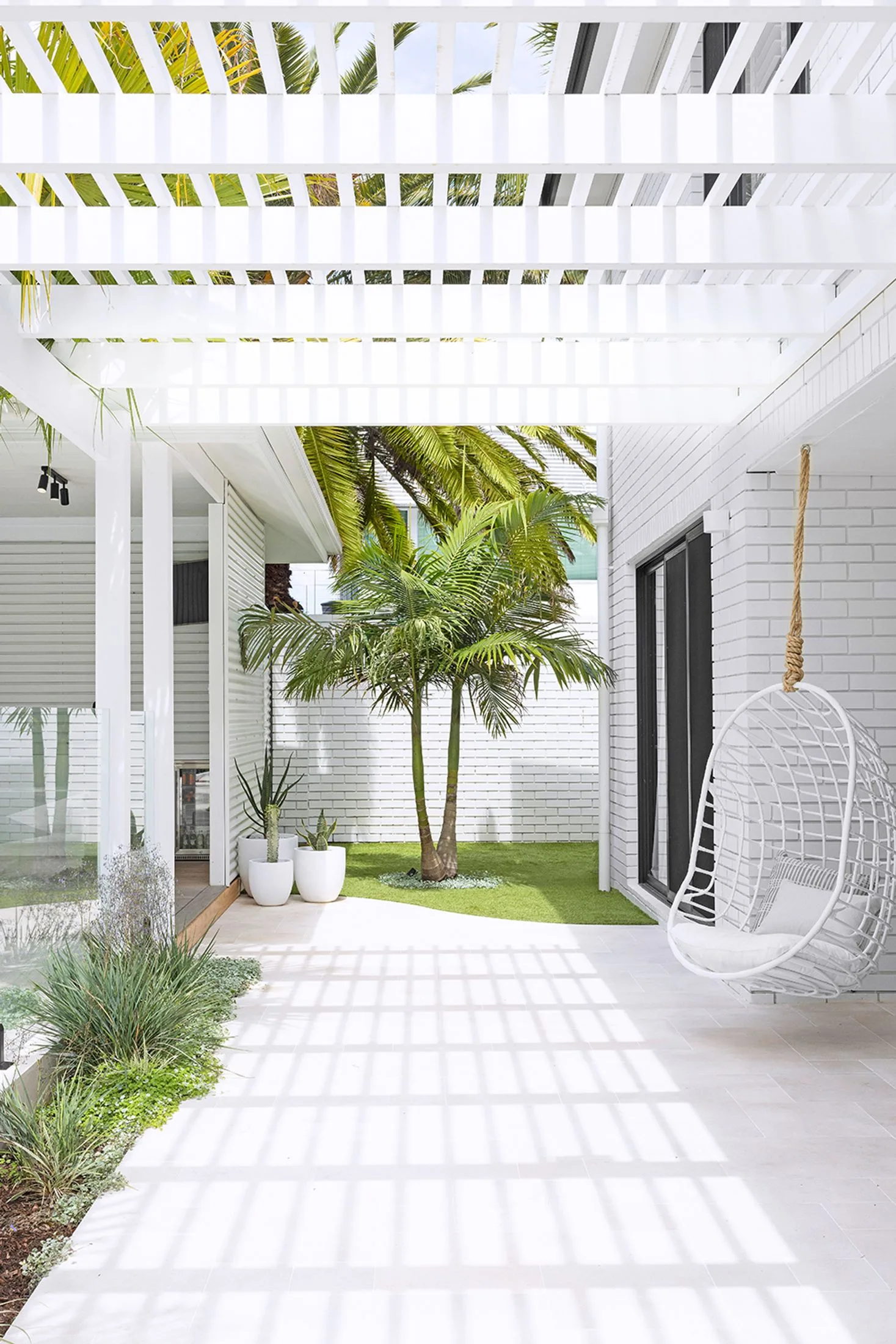 White brick home exterior with white hanging chair