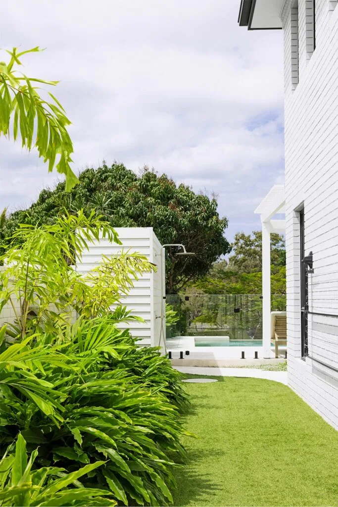 White home exterior with weatherboard cladding and lush landscaping and lawn