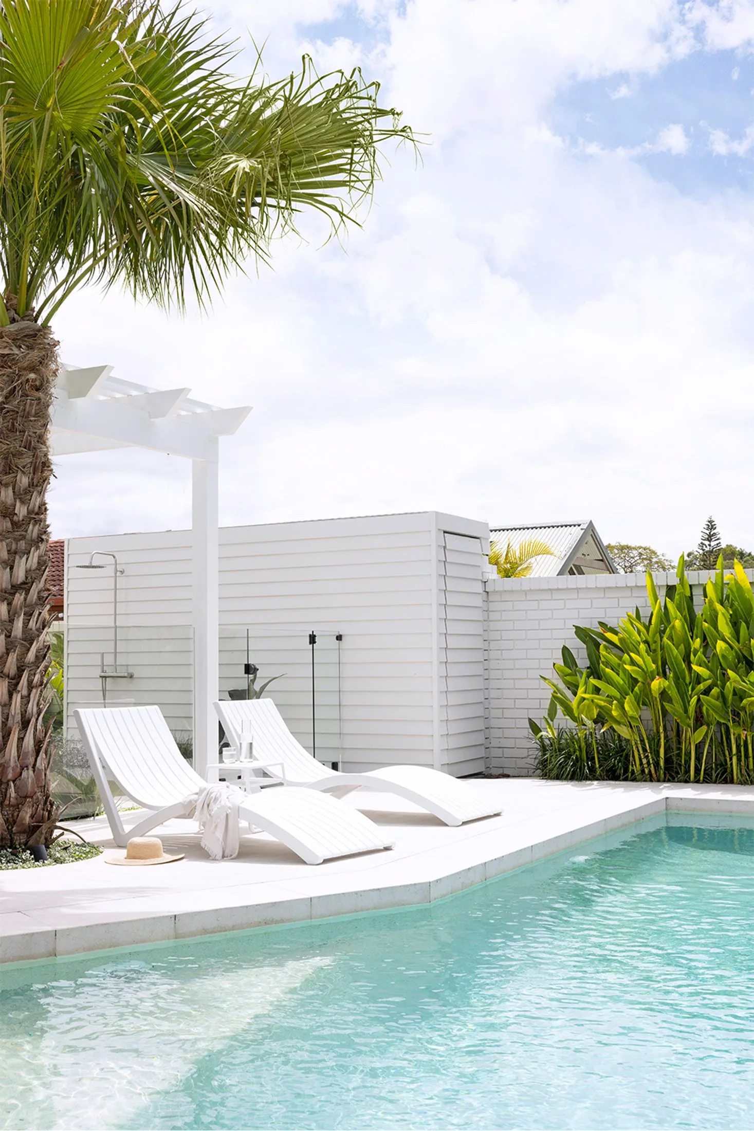 white brick exterior swimming pool with loungers