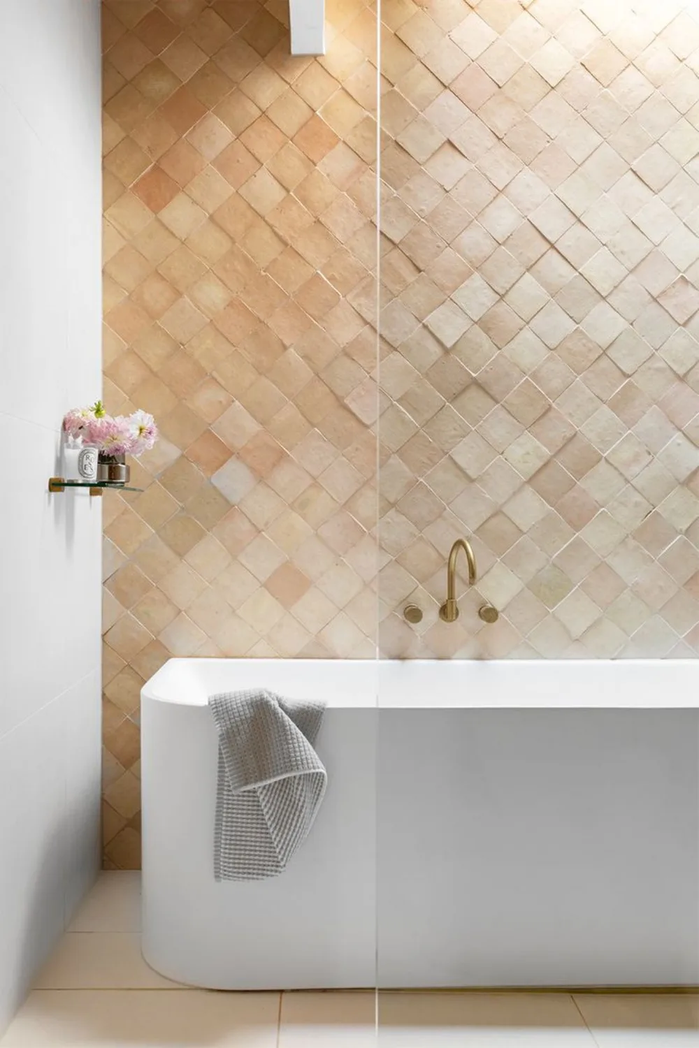 Freestanding bath tub with a tiled feature wall behind it