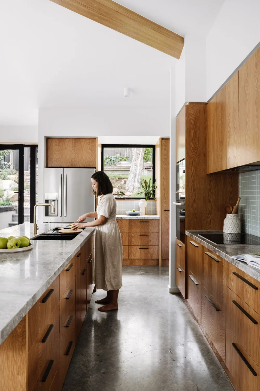 Woman standing in timber kitchen with indoor plant on window sill