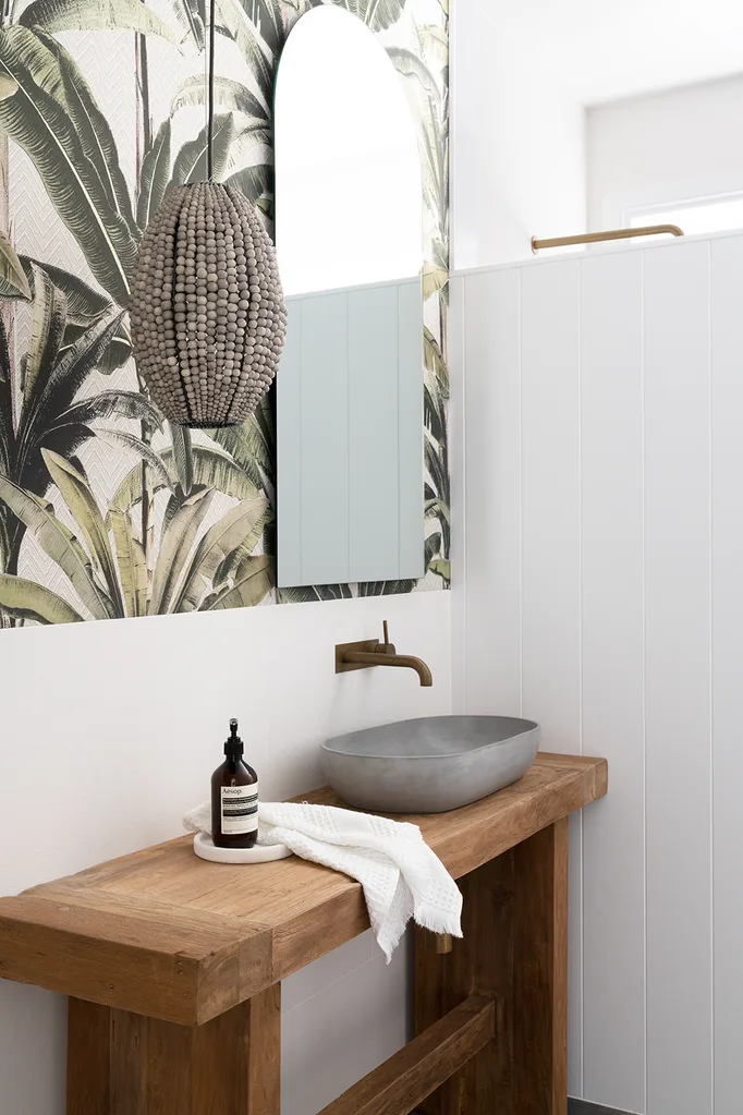 Coastal style powder room with timber vanity and tropical wallpaper