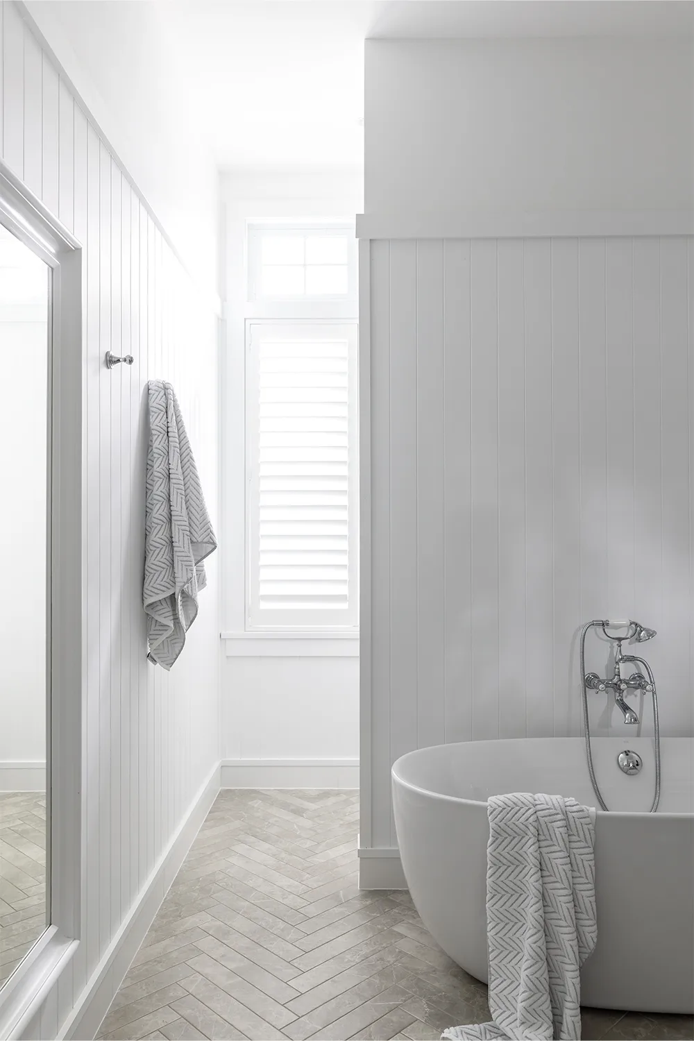 Hamptons style all white bathroom with herringbone marble-look floor tiles