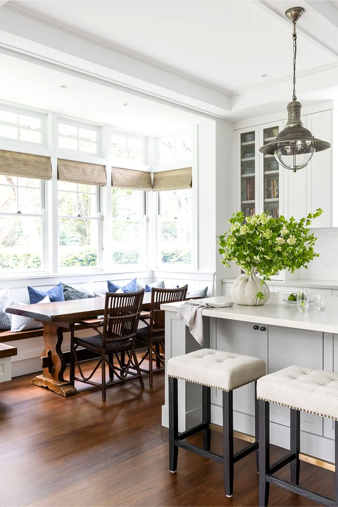 Hamptons style kitchen with breakfast nook and banquette seating around antique dining table