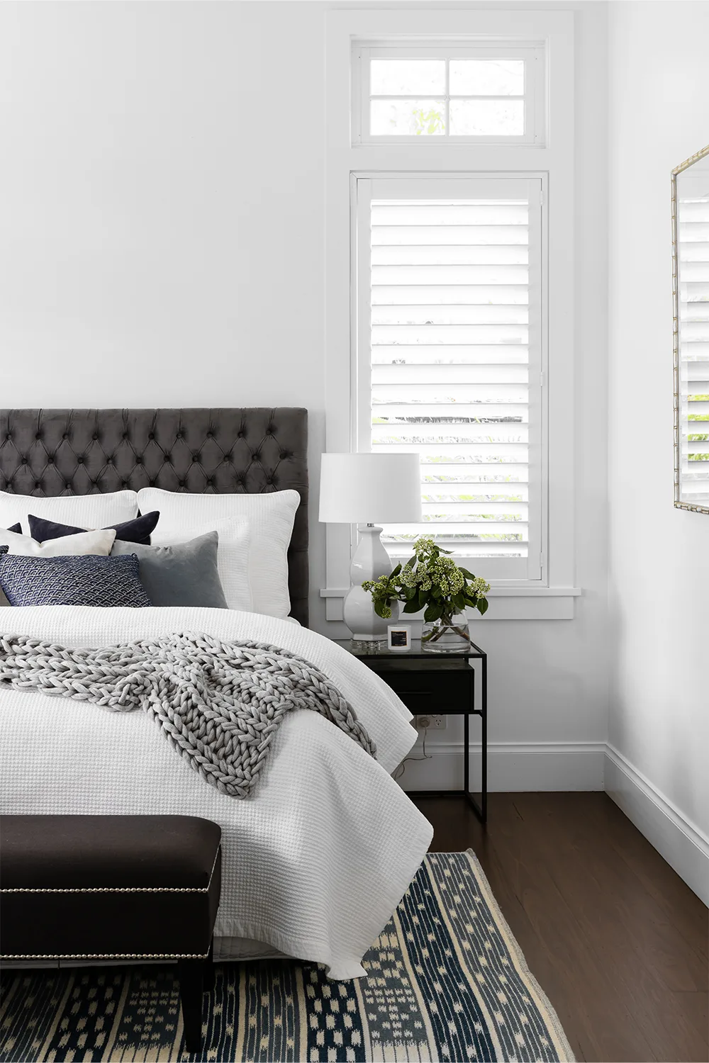 Hampont style bedroom with charcoal tufted bedhead and patterned rug