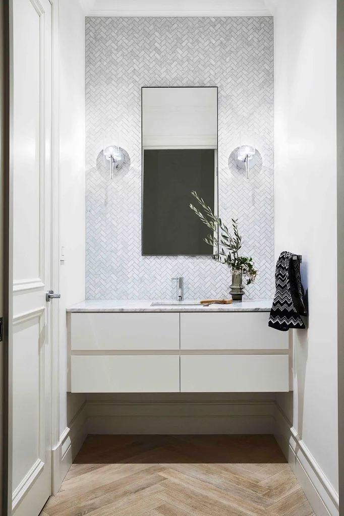 Powder room with herringbone marble wall tiles and timber herringbone floor