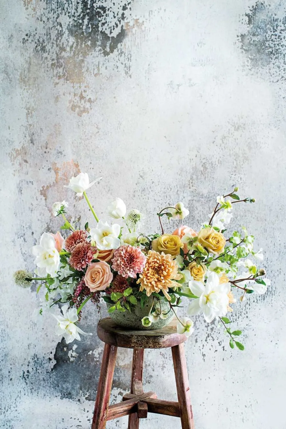 Flowers arranged in a vase on a wooden stool