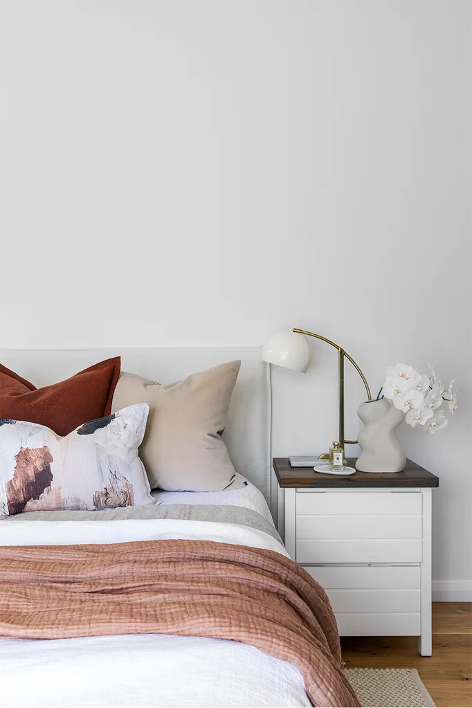 coastal style white bedroom with terracotta cushions and throw