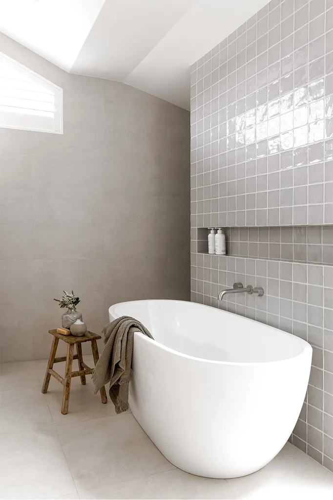 contemporary bathroom square grey tiles white oval bathtub timber bath stool