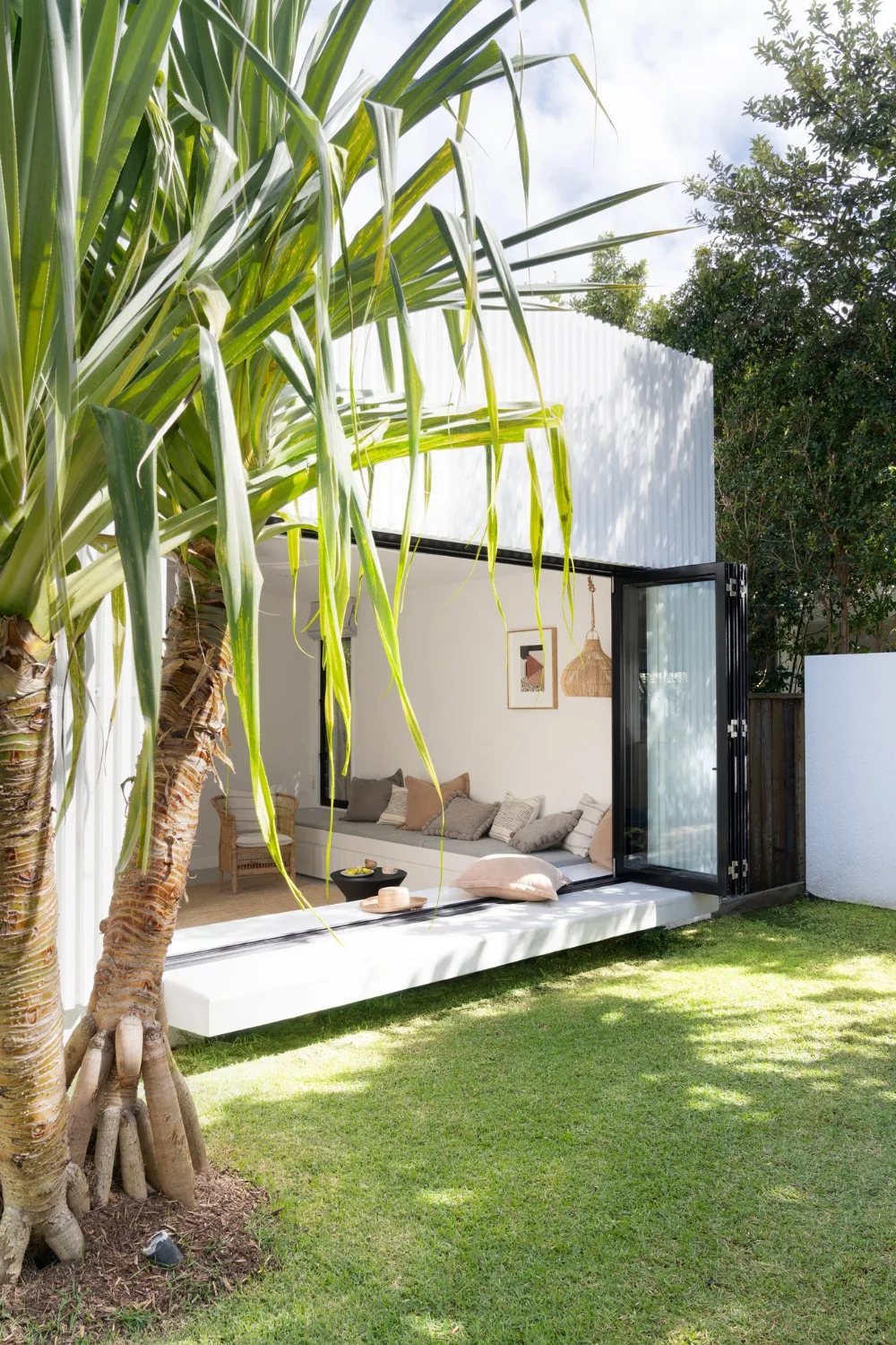 Rear of coastal home with bi-fold doors opening onto lawn