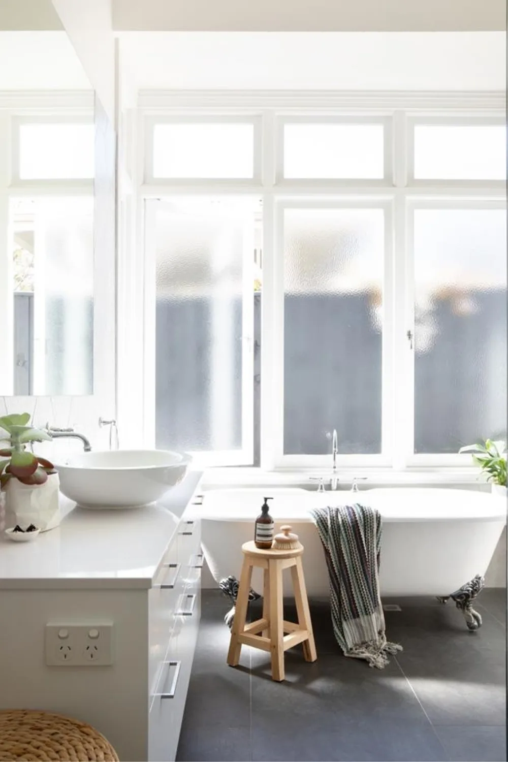 White bathroom with claw-footed tub and frosted windows