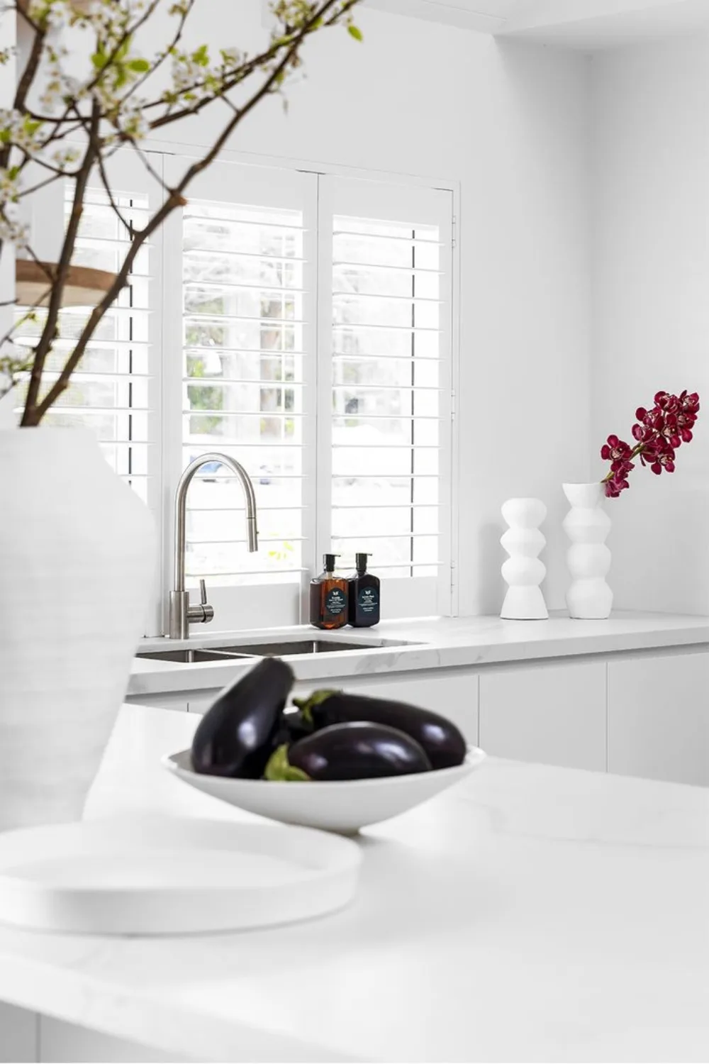 White kitchen with marble benchtops and plantation shutters