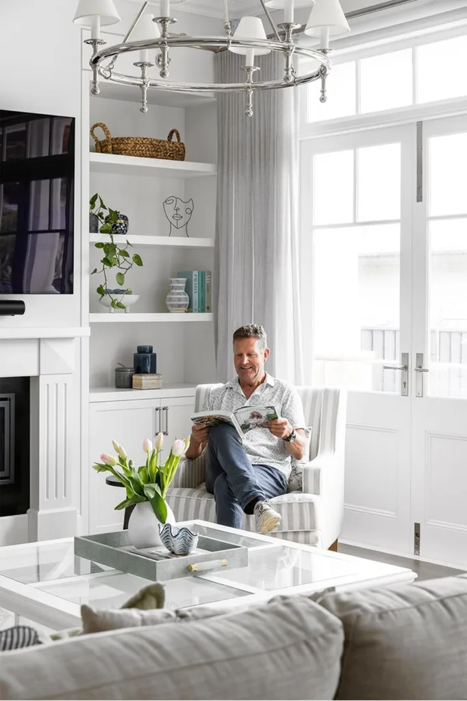 Man sitting in Hamptons style living room reading a magazine