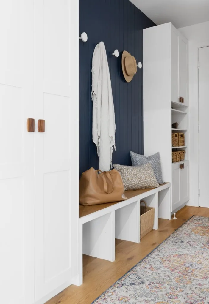 mudroom with white cabinetry and navy feature wall