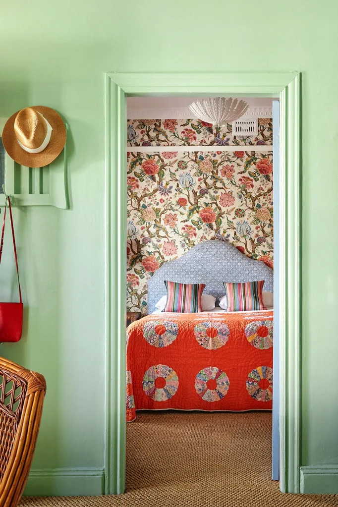 Colourful bedroom with patterned bedhead and floral wallpaper