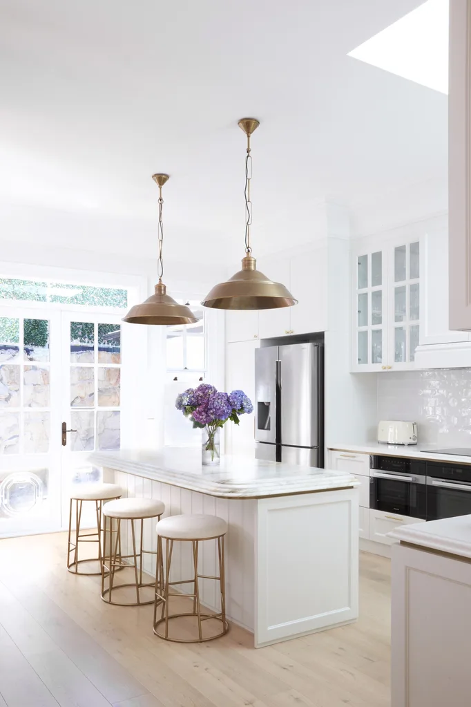 white kitchen island with brass pendants
