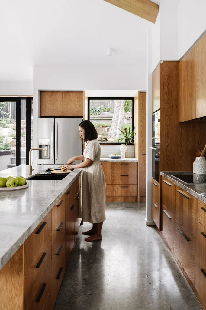 Woman in a timber and stone kitchen chopping at the sink.