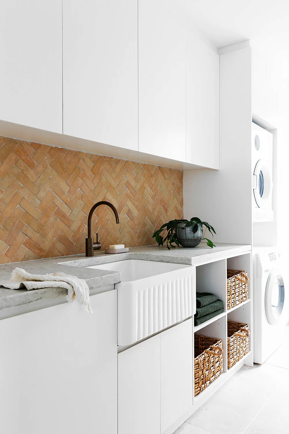 White and marble laundry with tiled terracotta splashback