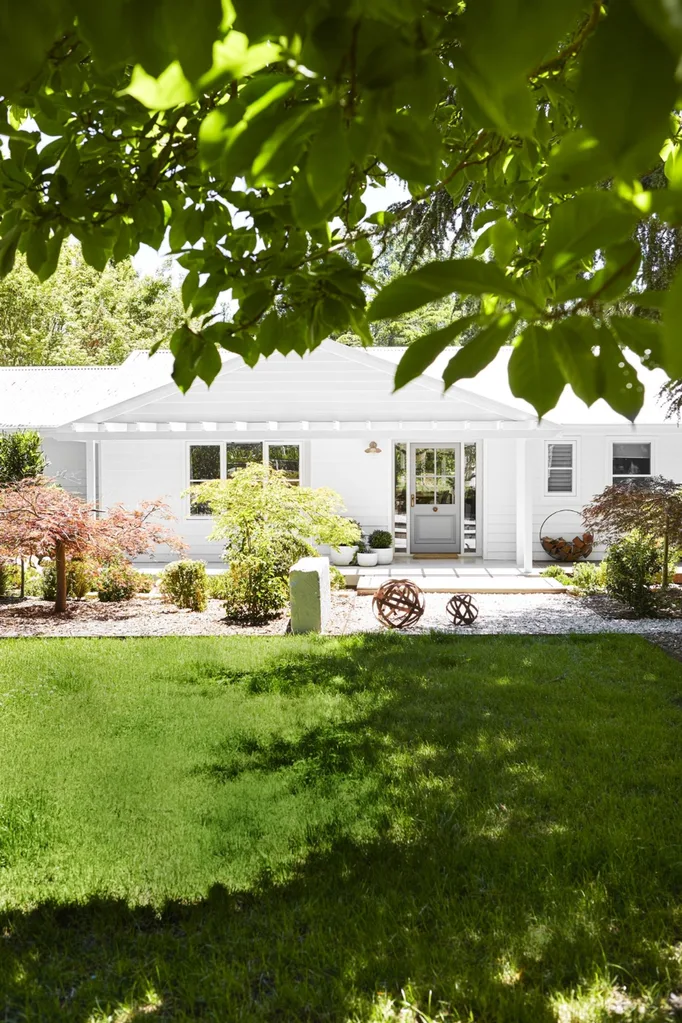 White house with lawn and shady tree in the backyard