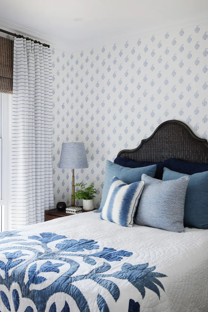 coastal bedroom with rattan headboard and navy floral wallpaper