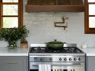 green cast iron pot on stove top with brass pot filler