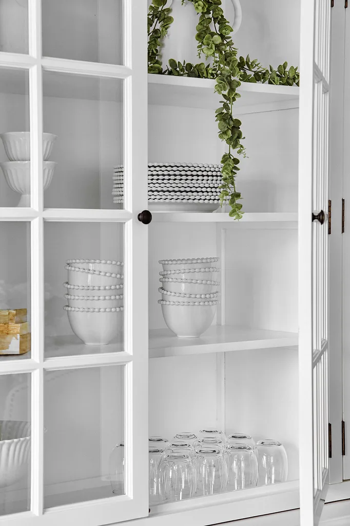 White kitchen hutch filled with glassware and crockery