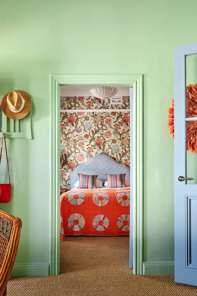 Colourful cottage bedroom with floral wallpaper and orange quilted coverlet