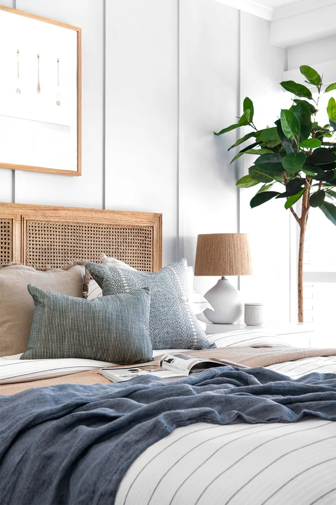 Coastal bedroom with blue and white bedding and rattan headboard