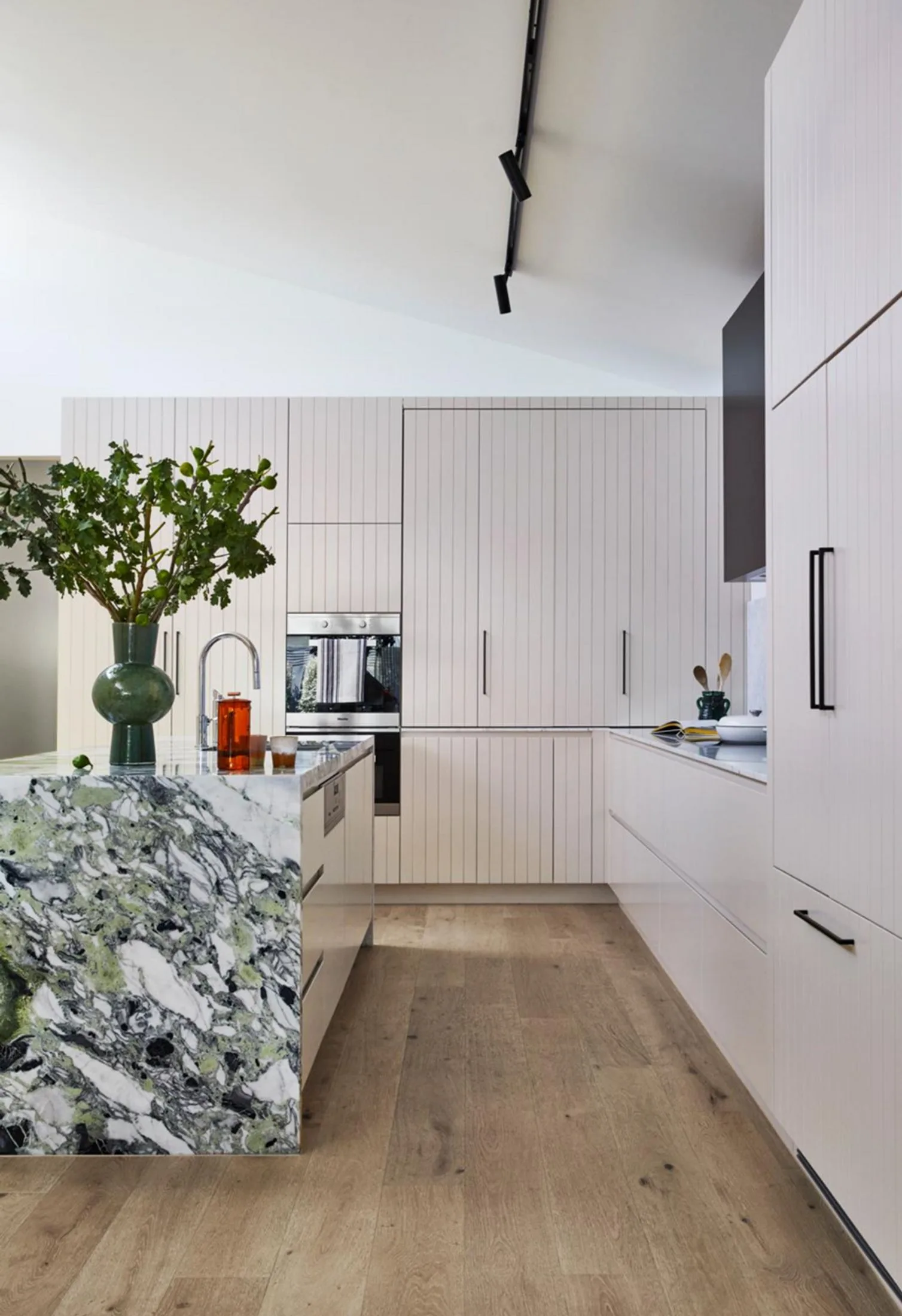 Modern kitchen with timber flooring and green marble kitchen island