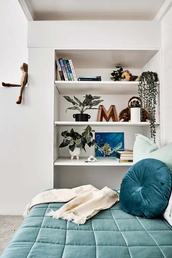 Collected pieces displayed on a bookshelf with teal velvet bedspread