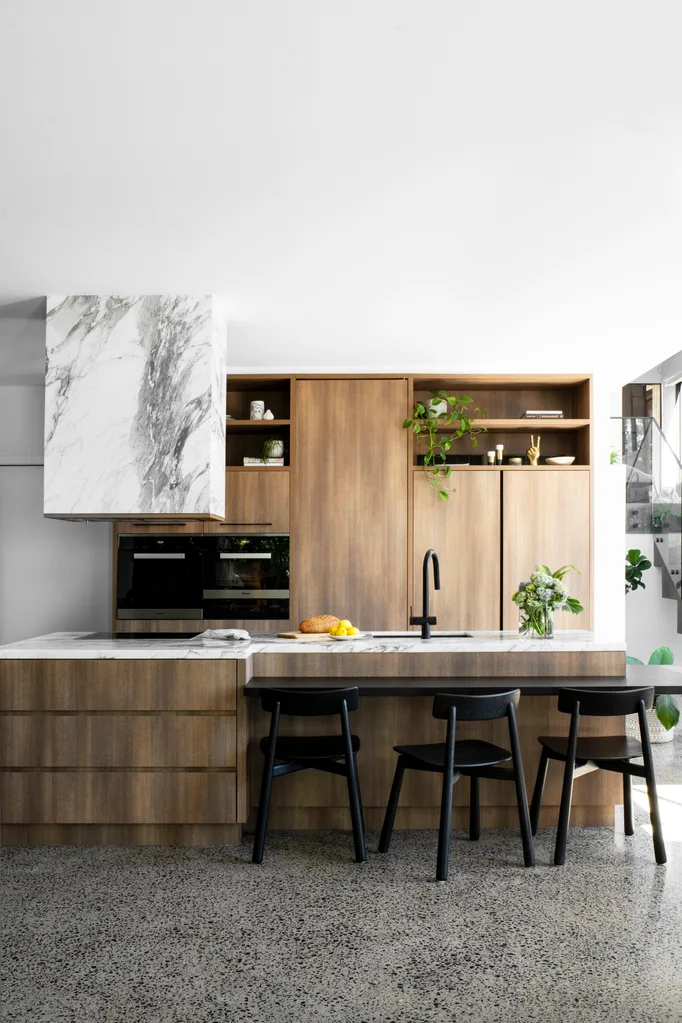 Wooden kitchen cabinetry with marble bench and range hood