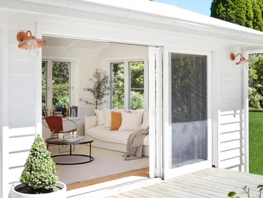 White multigenerational house with deck and gold wall lights