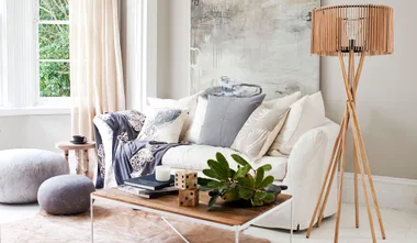Cozy living room with a white sofa, colorful pillows, a wooden coffee table, and a modern floor lamp.